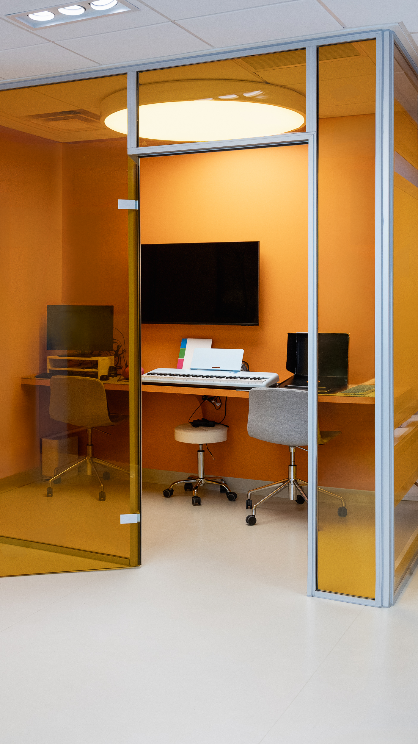 Orange-tinted music room with keyboard, computers, and seating